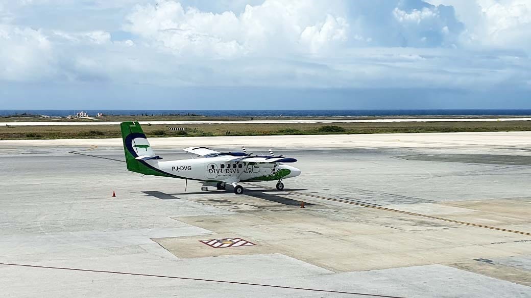Eine Propellermaschine der Fluggesellschaft Divi Divi Air auf dem Rollfeld des Flughafens Hato mit dem Divi Divi Baum als Logo - zu sehen auf der Heckflosse des Flugzeugs