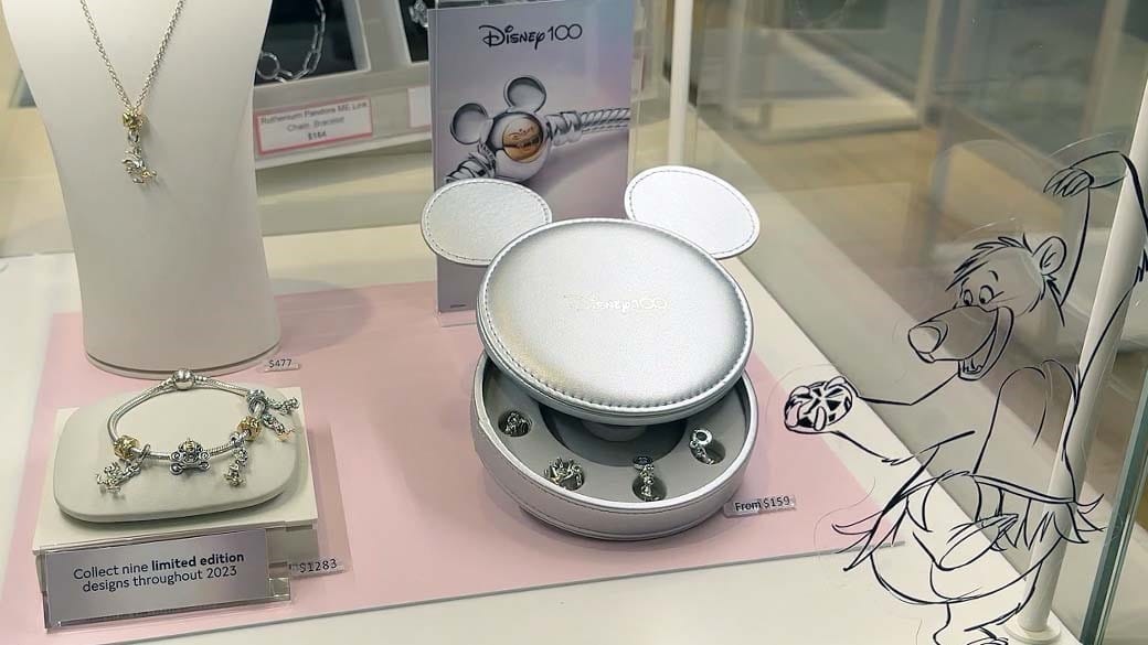Blick in eine PANDORA Vitrine mit der Disney Kollektion: Kette, Charm-Armband und einzelne Charms in einer silbernen Mickey Maus Schatulle